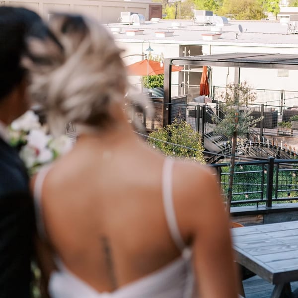 Couple on a rooftop overlooking an outdoor patio with string lights and seating.