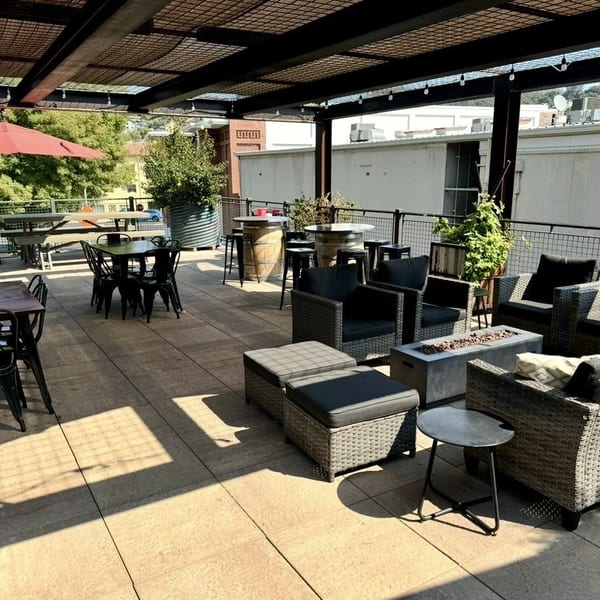 An outdoor patio with various seating, including dining tables, lounge chairs, and a fire pit.
