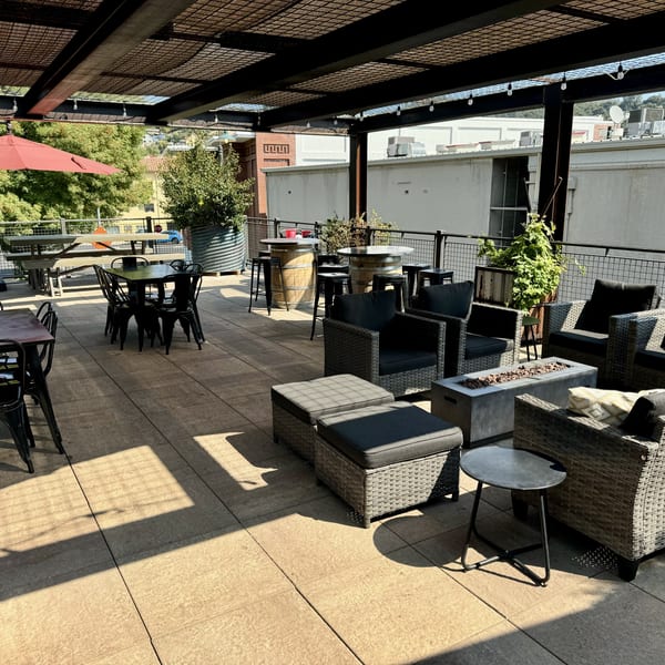 Spacious outdoor patio with various seating, including dining tables, lounge chairs, and barrel high-tops.