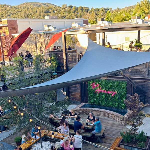 Overhead view of a lively outdoor patio with people dining at tables under shade sails.